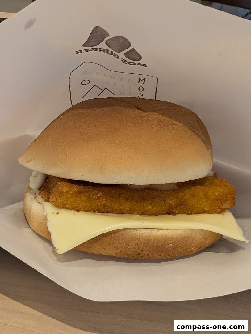 A delicious MOS Burger fish fillet sandwich with cheese and sauce on a bun.