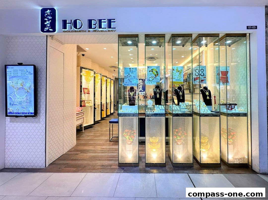 Ho Bee Goldsmith & Jewellery shop front with illuminated displays of necklaces and gold items.