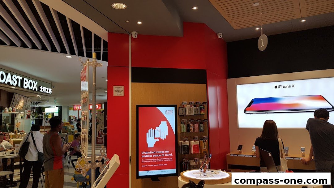 Customers browse phones at a Singtel Exclusive Retailer with an iPhone X display.