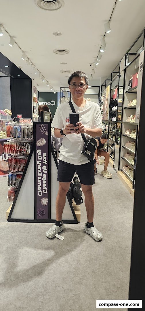 A man stands in a Crocs store, showcasing the latest footwear and accessories.