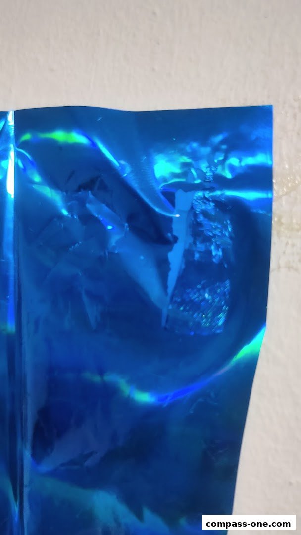 Close-up of a shiny blue holographic material with a textured white background.