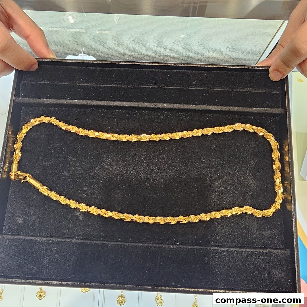 A gold rope chain necklace displayed in a black velvet jewelry box.