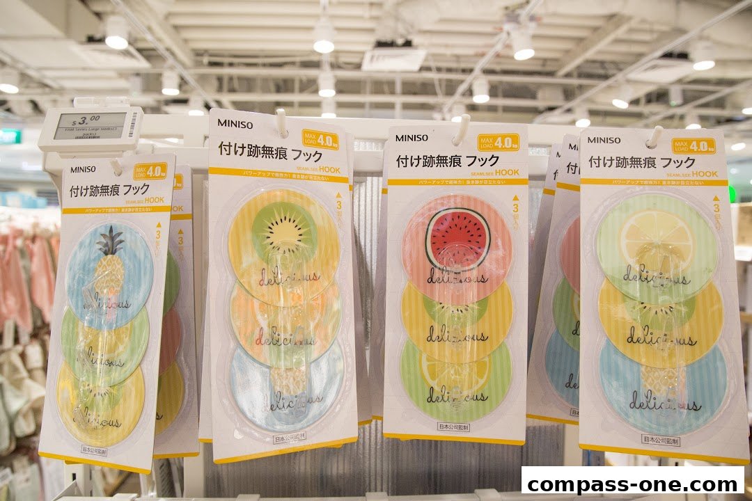 Packs of fruit-themed adhesive hooks with 'delicious' text displayed on a store shelf.