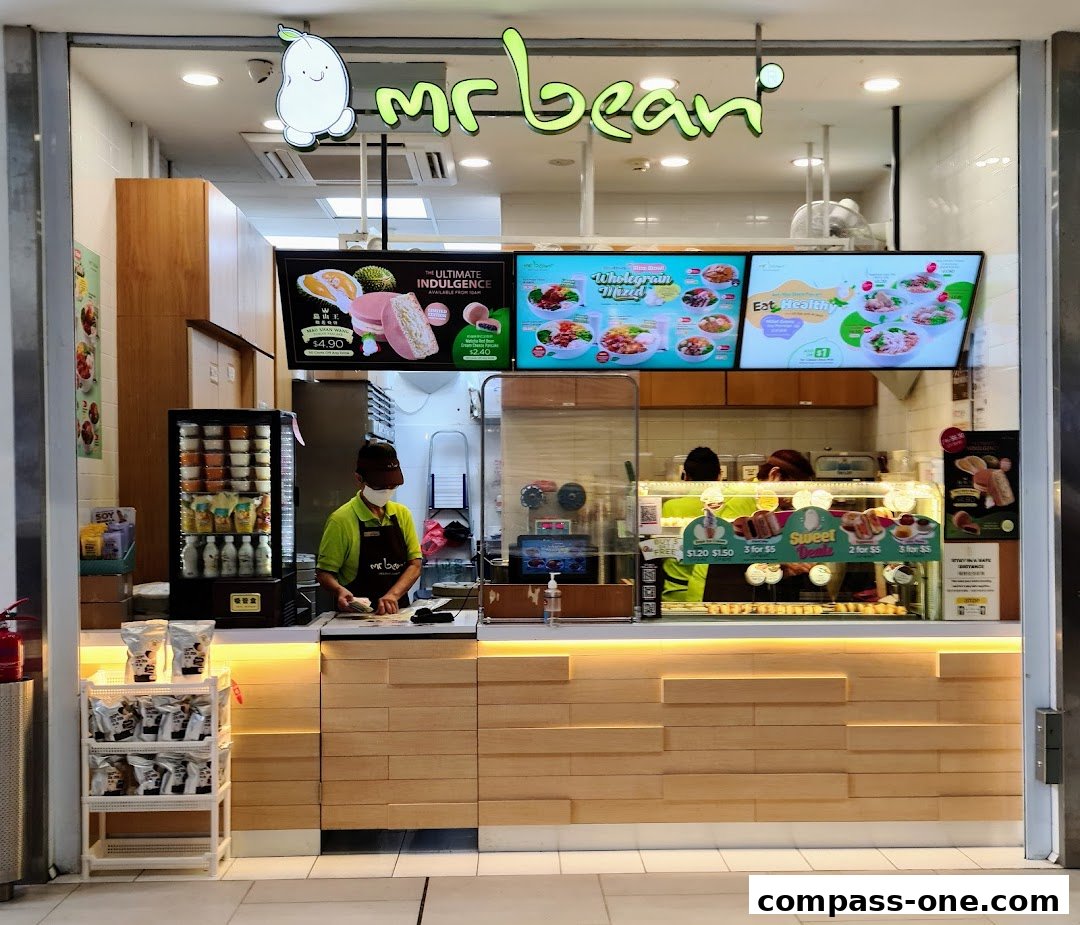 Mr Bean shop front with digital menus displaying food and drinks, and a staff member behind the counter.