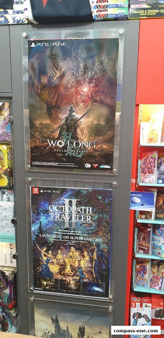 Posters for video games 'Wo Long: Fallen Dynasty' and 'Octopath Traveler II' displayed in a store.