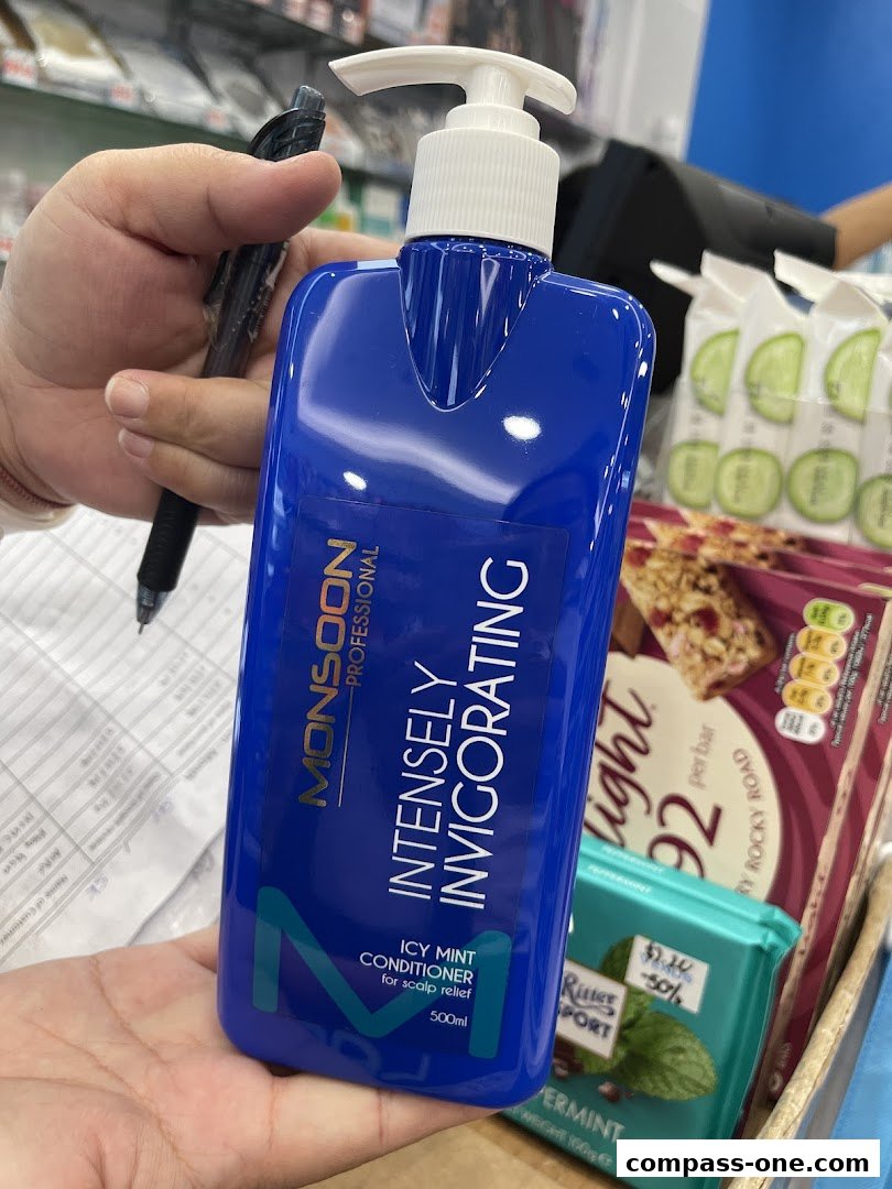 A hand holds a blue bottle of Monsoon Professional Icy Mint Conditioner.