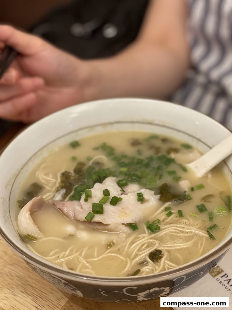A close-up shot of a delicious bowl of fish noodle soup with fresh ingredients.
