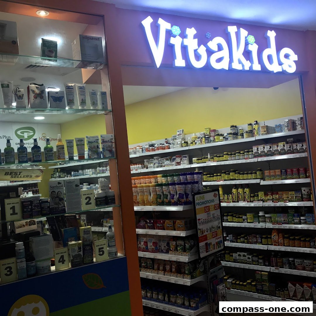 The entrance of VitaKids, a shop selling health products and supplements, with shelves stocked with various items.