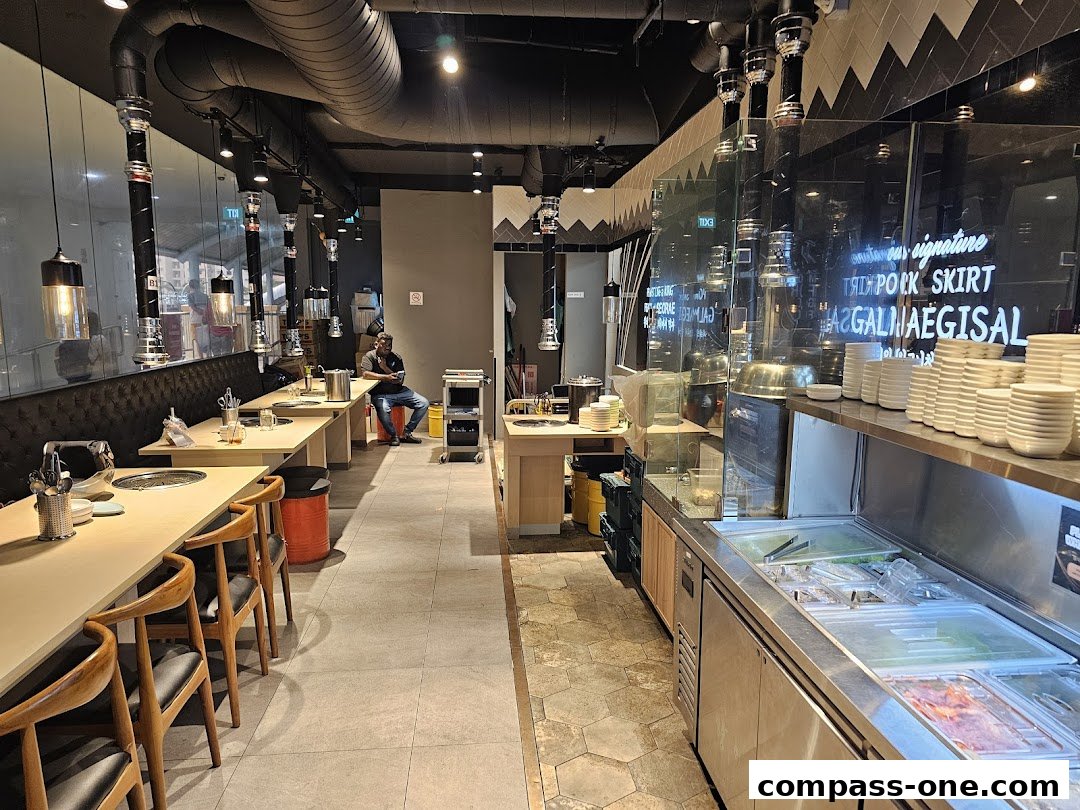 Interior of a Korean BBQ restaurant with tables, chairs, and a food display counter.