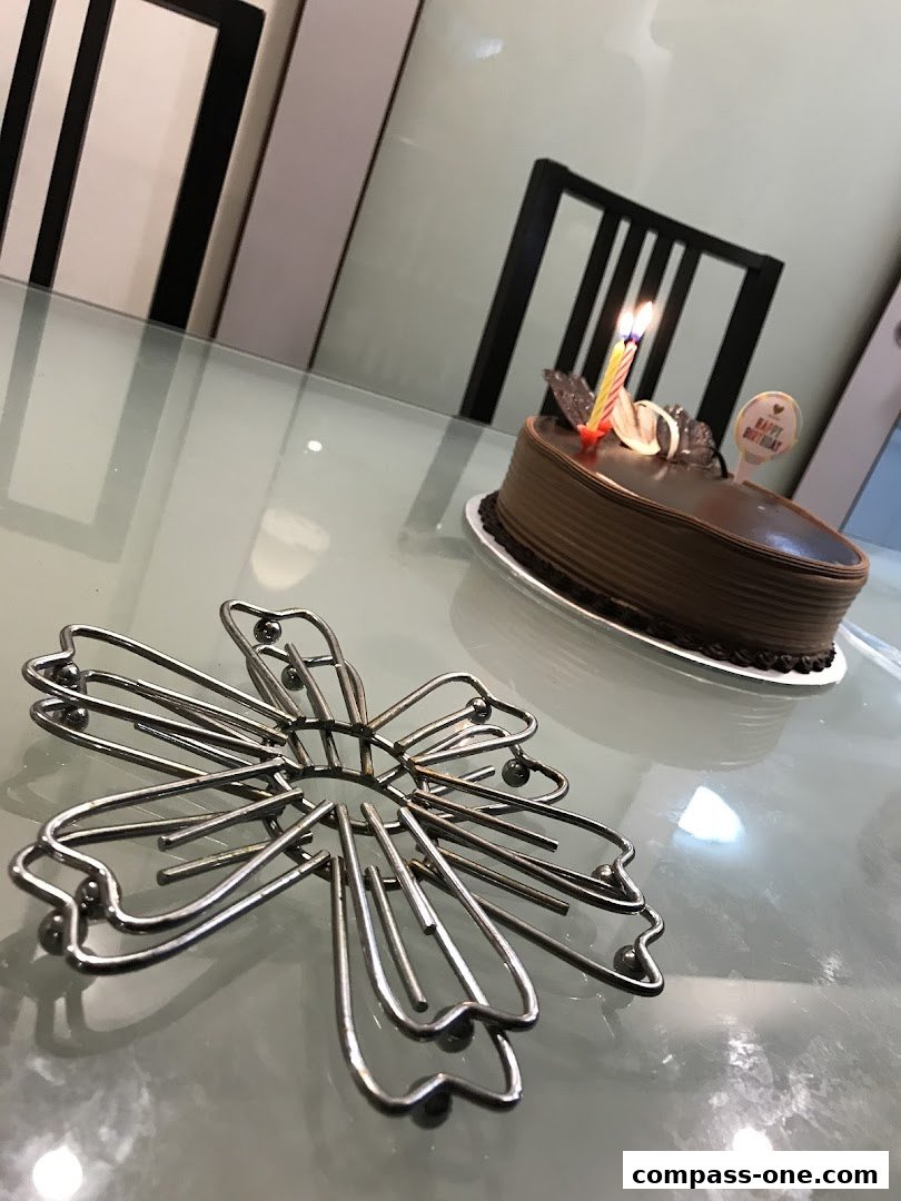 A chocolate cake with lit candles and a 'Happy Birthday' topper sits on a table.