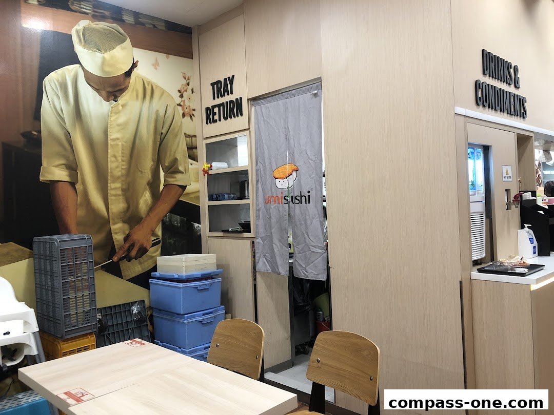 Interior view of a sushi restaurant with a large mural of a chef and a branded curtain.