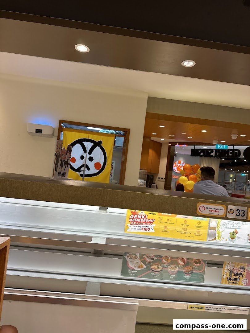 Interior view of Genki Sushi with a Noren curtain and a display of food items.