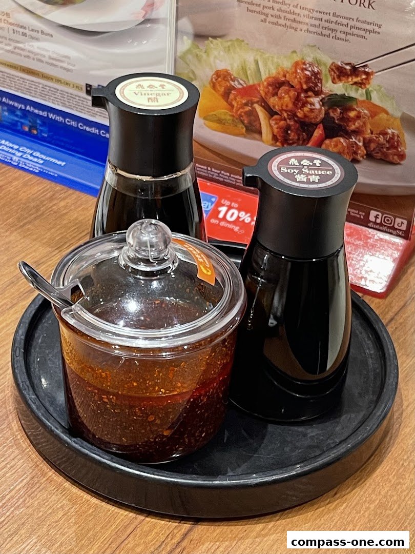 Condiments including chili oil, soy sauce, and vinegar on a table at Din Tai Fung.