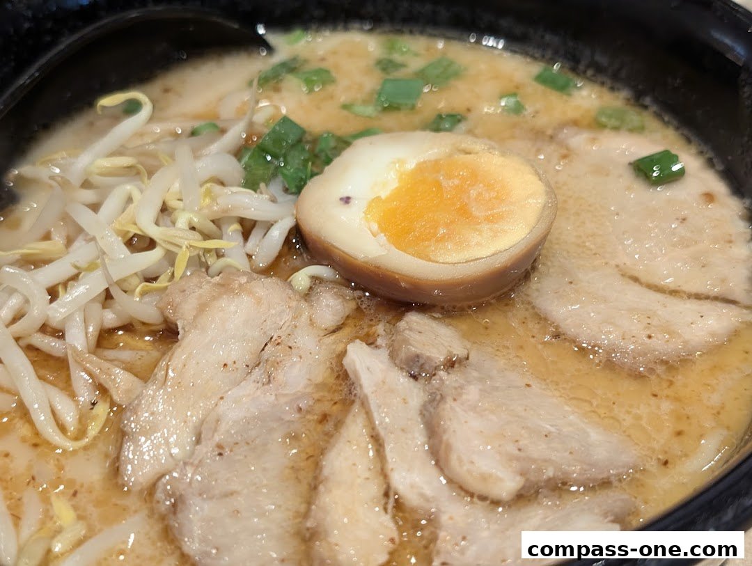 A close-up shot of a steaming bowl of Ajisen Ramen with pork, egg, and bean sprouts.