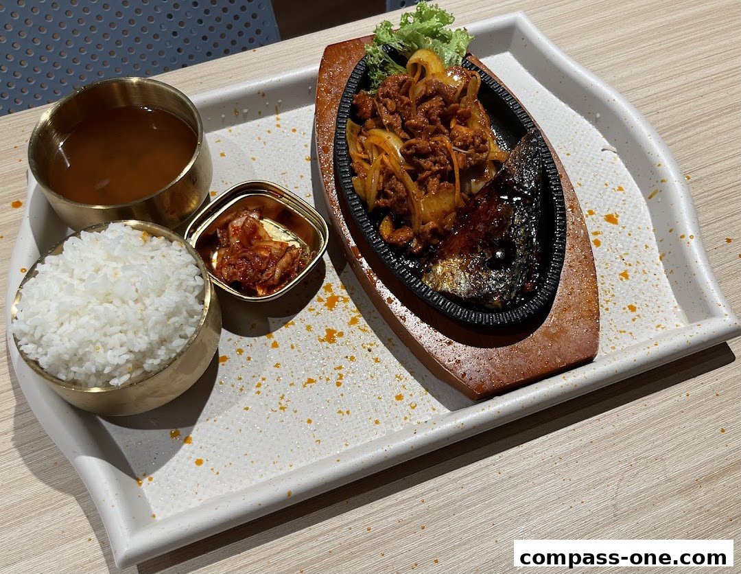 A sizzling Korean dish with rice, kimchi, and soup served on a tray.