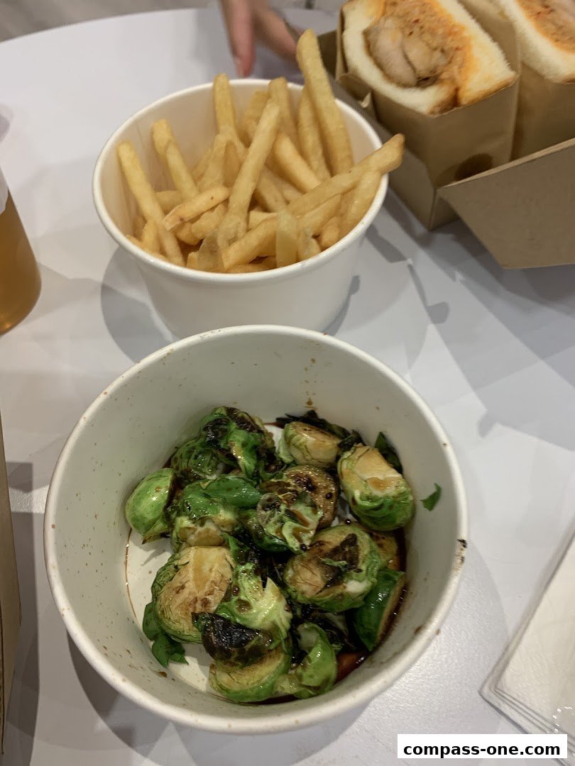 A close-up of a meal featuring french fries and glazed Brussels sprouts.