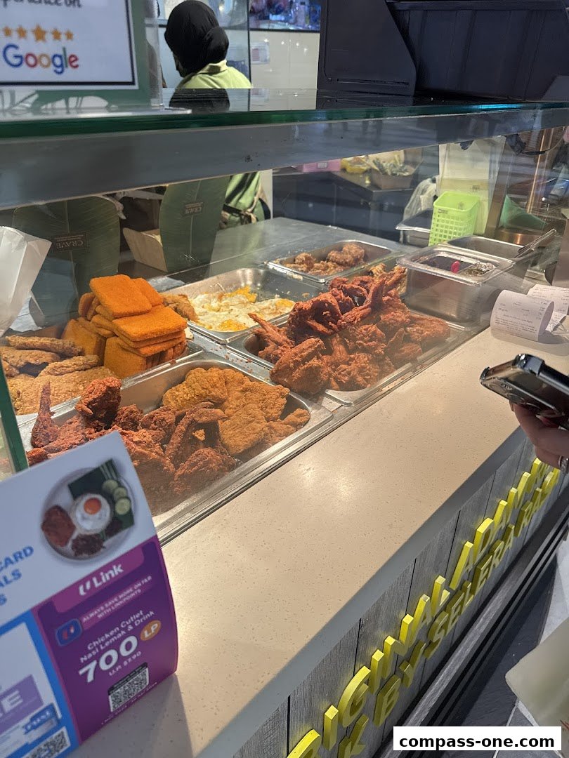 A display of fried chicken and nasi lemak at a food counter.