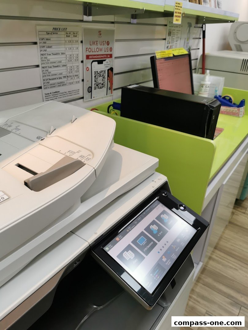 A close-up of a photocopier with a price list and social media QR code visible.