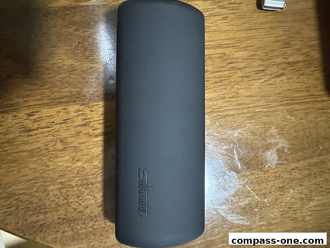 A dark gray glasses case with the Silhouette logo embossed on it, placed on a wooden surface.