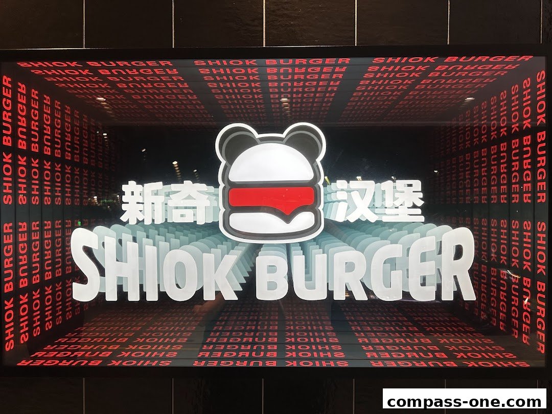 The Shiok Burger shop sign features a stylized burger logo and the shop name in large, illuminated letters.