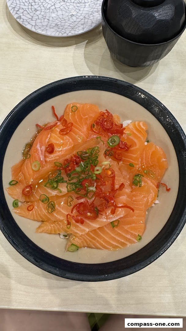 A close-up of a delicious salmon donburi dish with chili and spring onions.