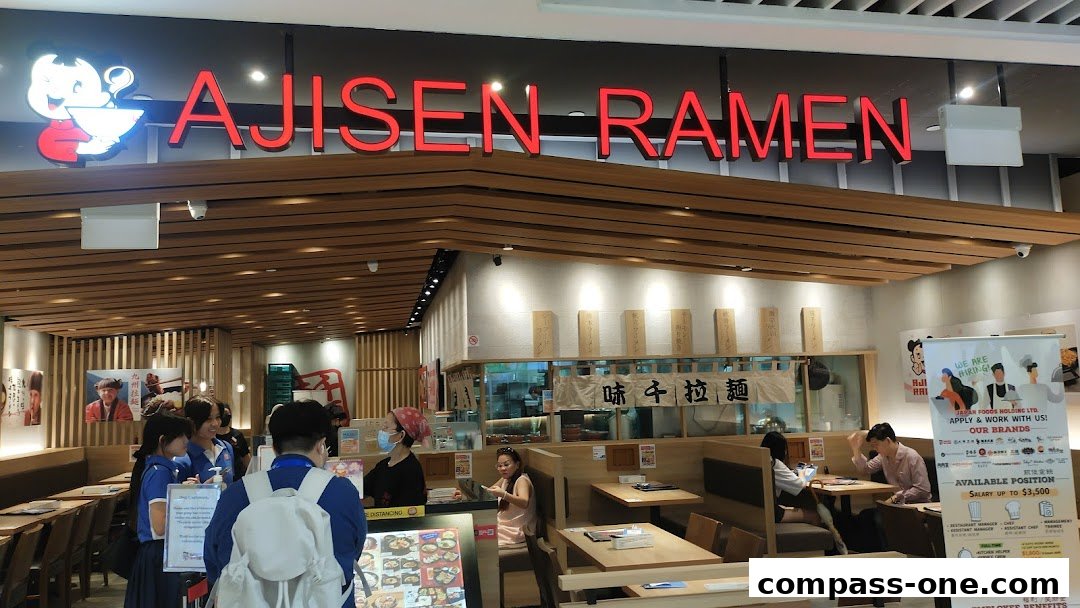 The interior of Ajisen Ramen restaurant with customers and staff, showcasing the brand's signage and seating.