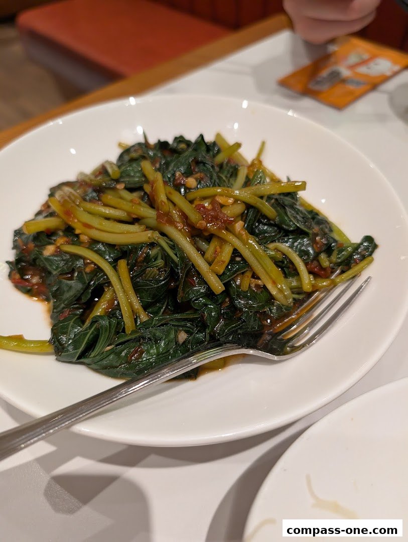 A plate of stir-fried greens with garlic and chili, served with a fork.