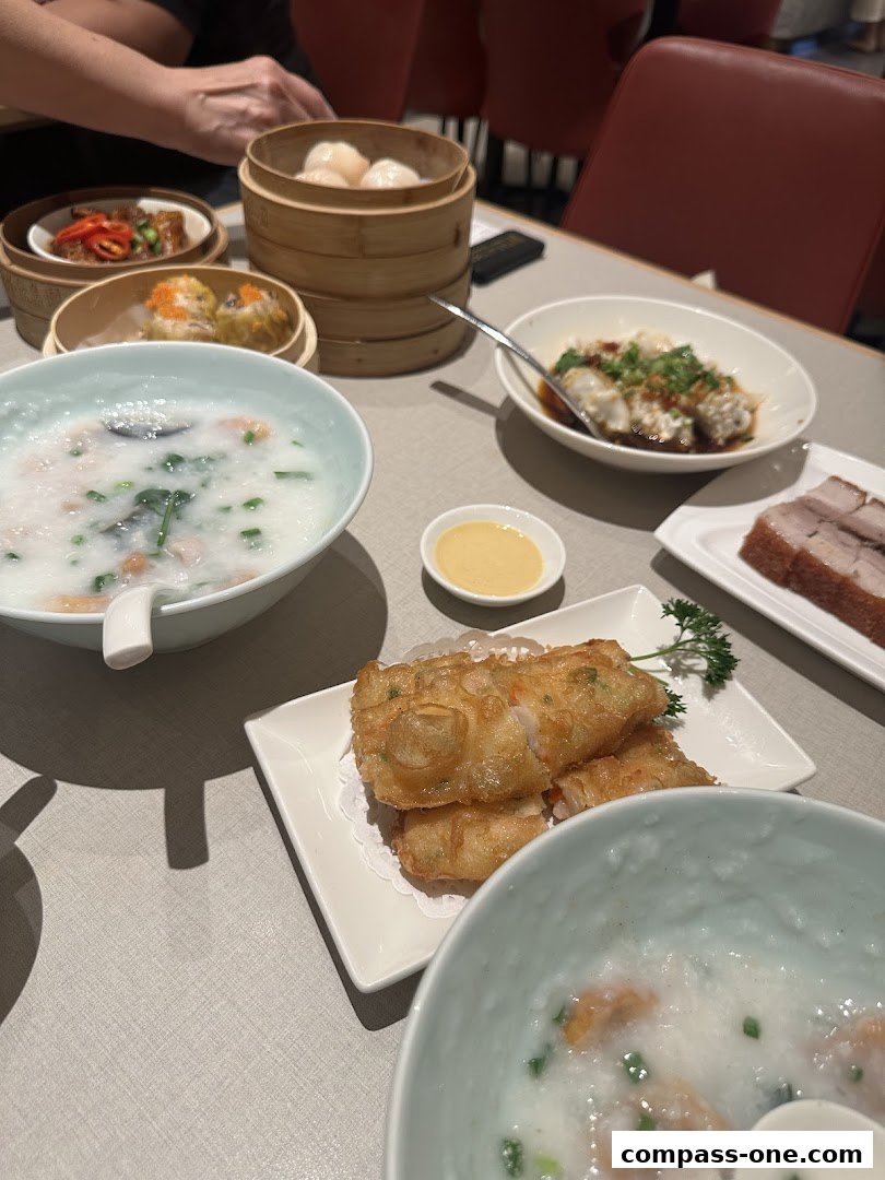A table laden with various Cantonese dishes, including dim sum, congee, and fried items.