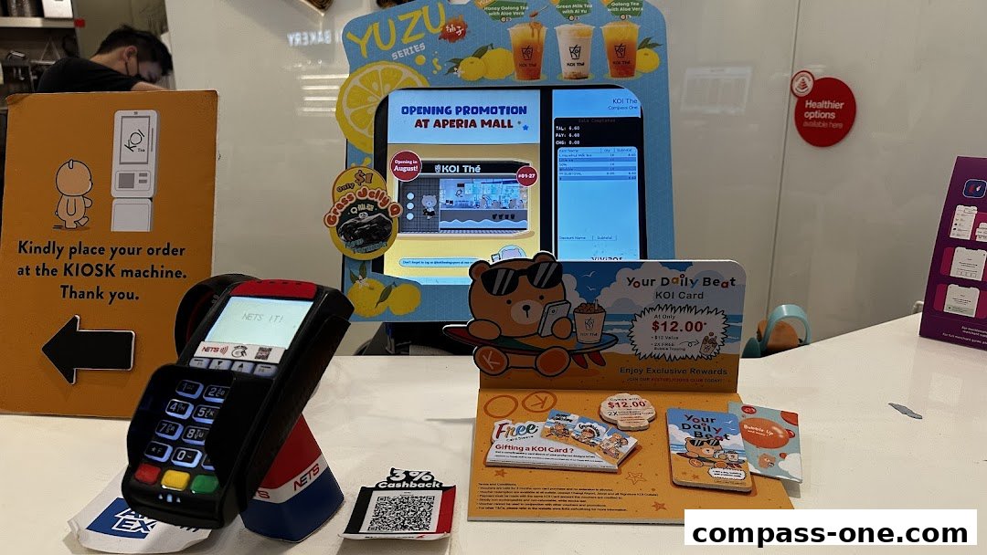 A KOI Thé shop with a kiosk, payment terminal, and promotional materials.