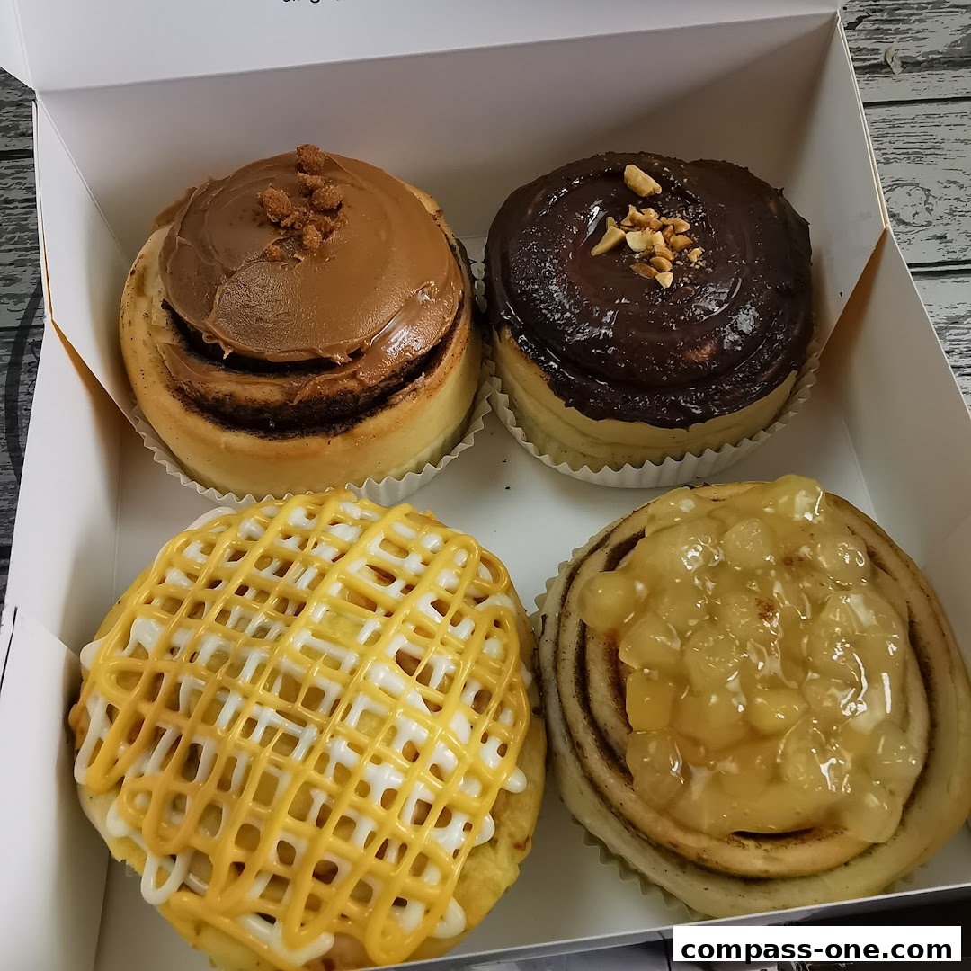 A box of four delicious cinnamon rolls with different toppings.