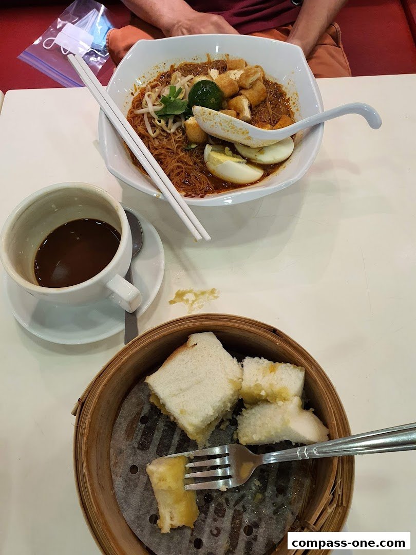 A bowl of noodles and a basket of toast with a cup of coffee.