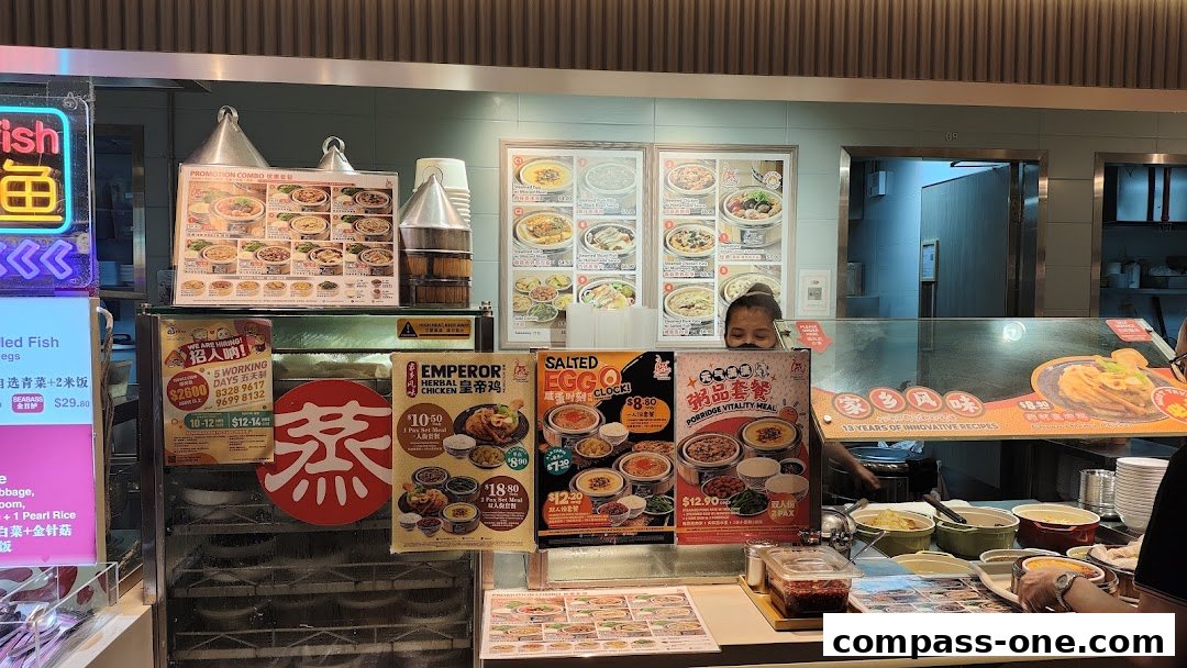 A food stall counter displaying various promotional posters and food items, with staff visible.