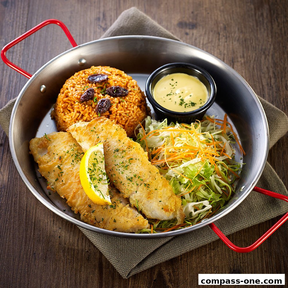 A close-up shot of a delicious fish and rice dish served in a metal pan.