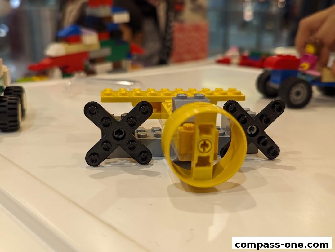 Close-up of a LEGO creation with wheels and a yellow propeller-like piece.