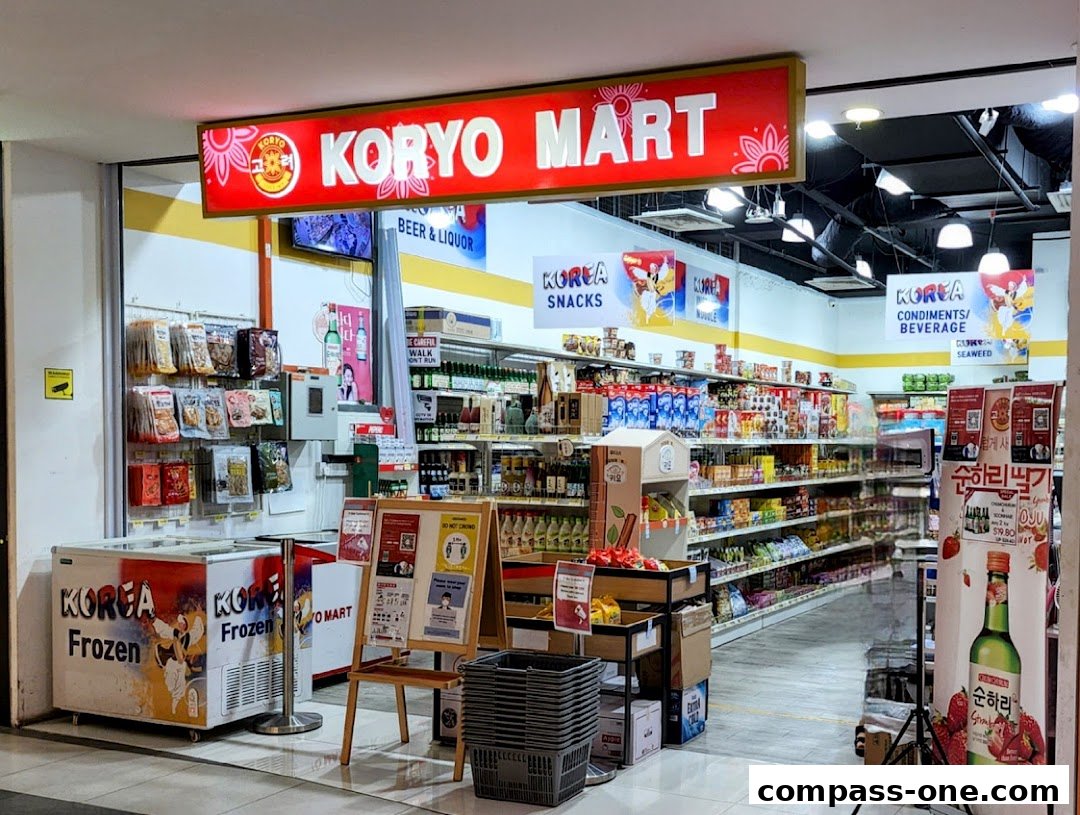 The entrance of Koryo Mart, a Korean grocery store, showcasing various products and signage.