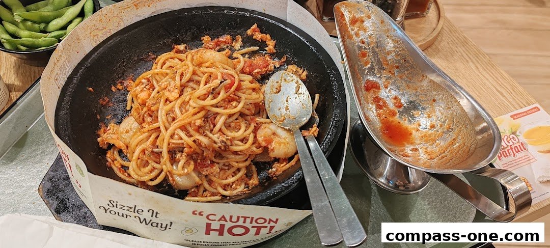 A sizzling plate of spaghetti with shrimp and a side of edamame, served at Pepper Lunch.