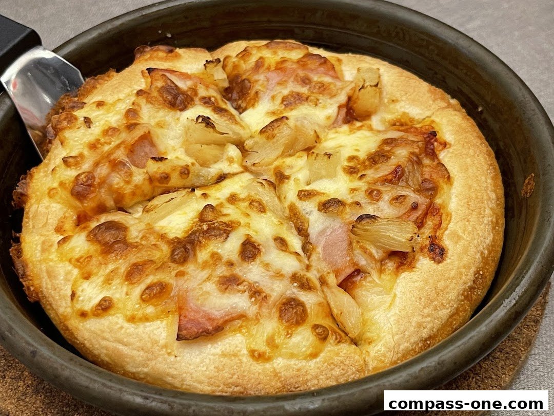 A close-up shot of a delicious Hawaiian pizza being served from a pan.