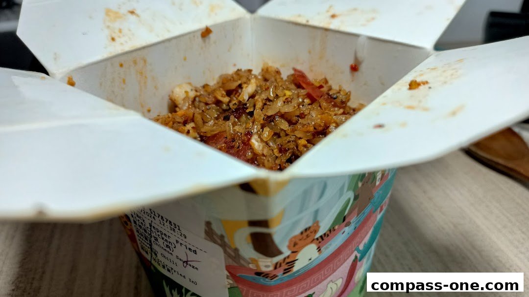 A close-up of a takeaway box filled with fried rice and chicken.