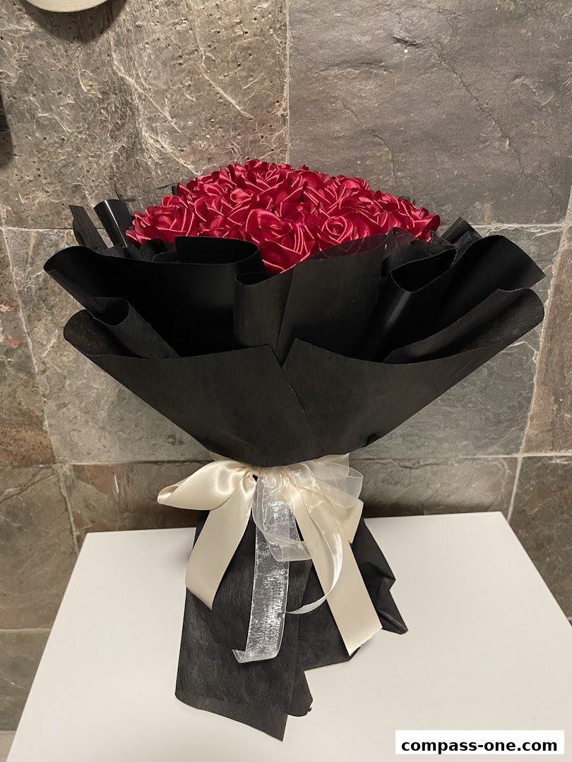 A beautiful bouquet of red roses wrapped in black paper with a cream ribbon.
