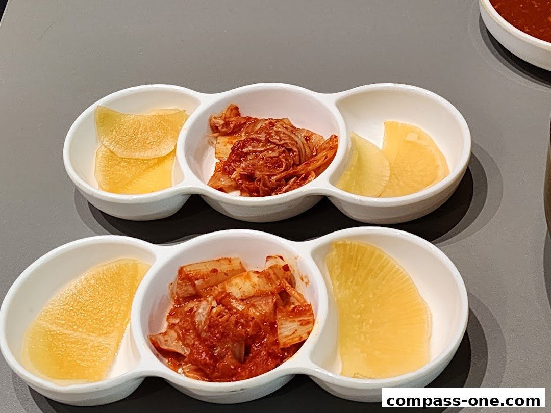 Two sets of white dishes containing kimchi and pickled radish slices.