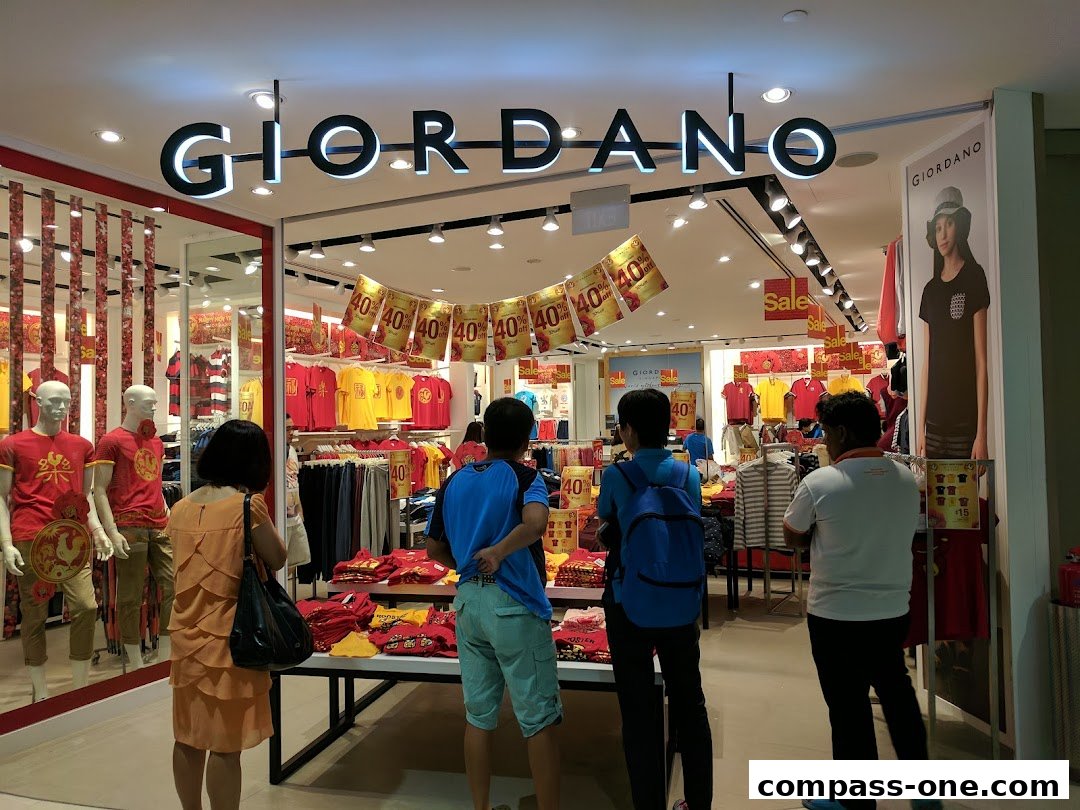 The interior of a Giordano clothing store with mannequins and racks of apparel on display.