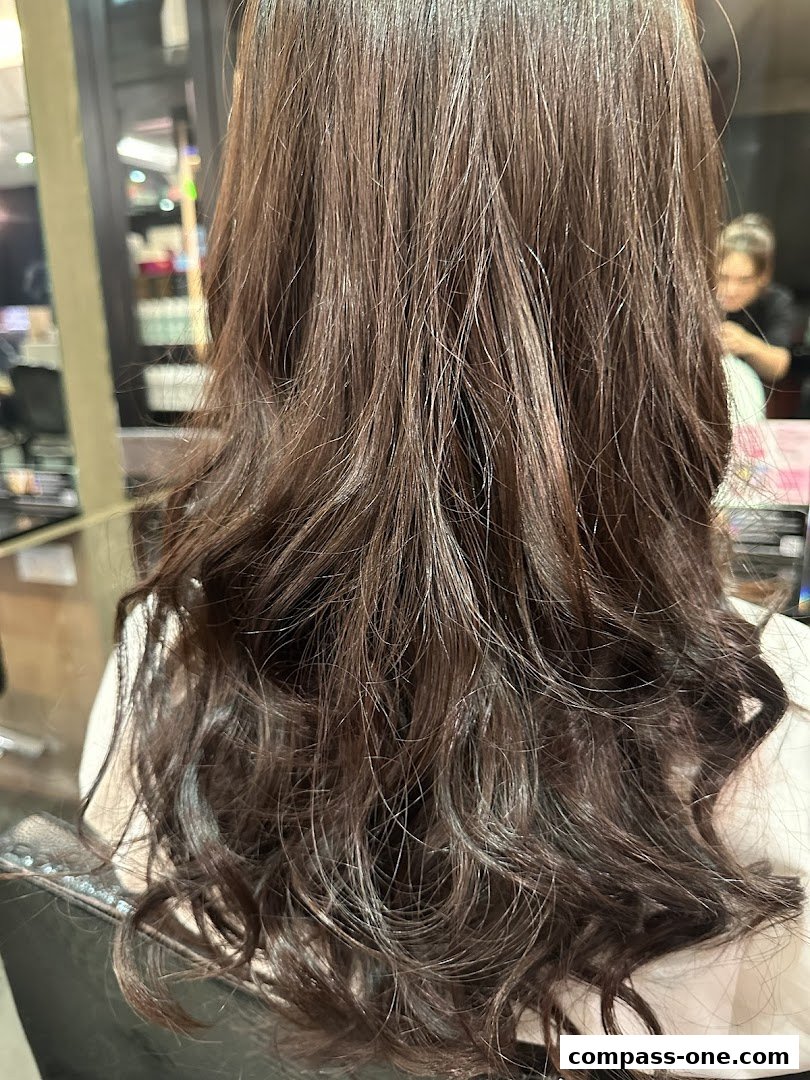 A person's long, dark, wavy hair styled in a salon.
