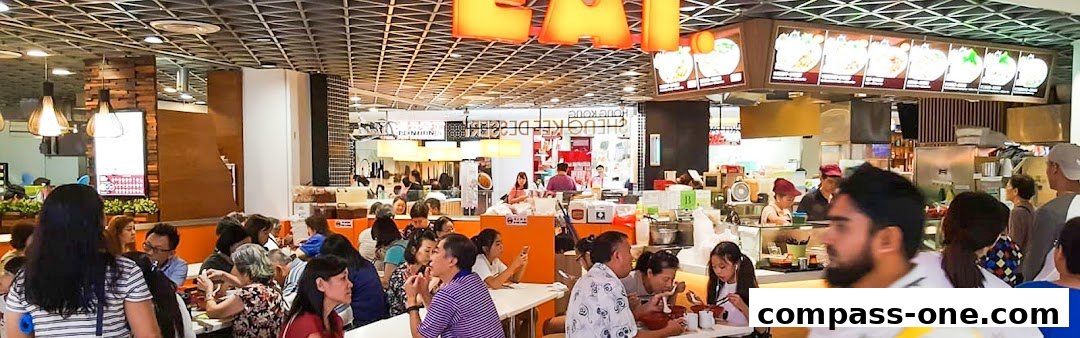 A busy food court with people dining and ordering at the 'EAT.' restaurant.