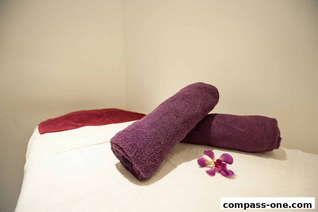 A massage bed prepared with clean towels and a delicate orchid flower.