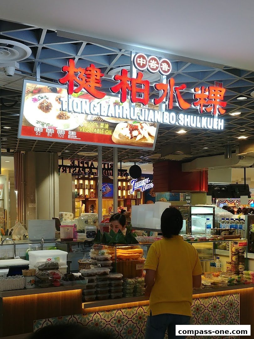 A food stall with a bright sign and display of food items, with customers being served.