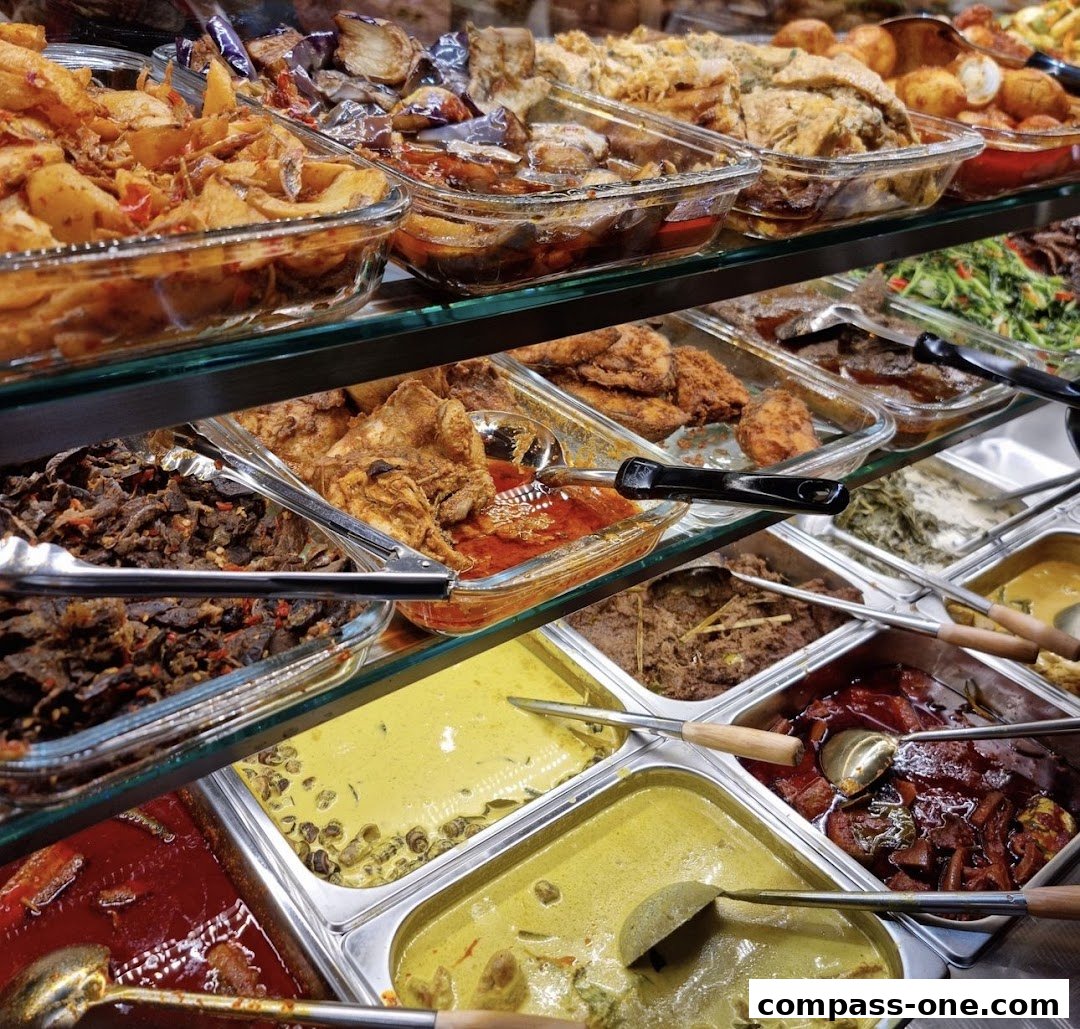 A display of various delicious Malay dishes in glass and metal trays, ready to be served.