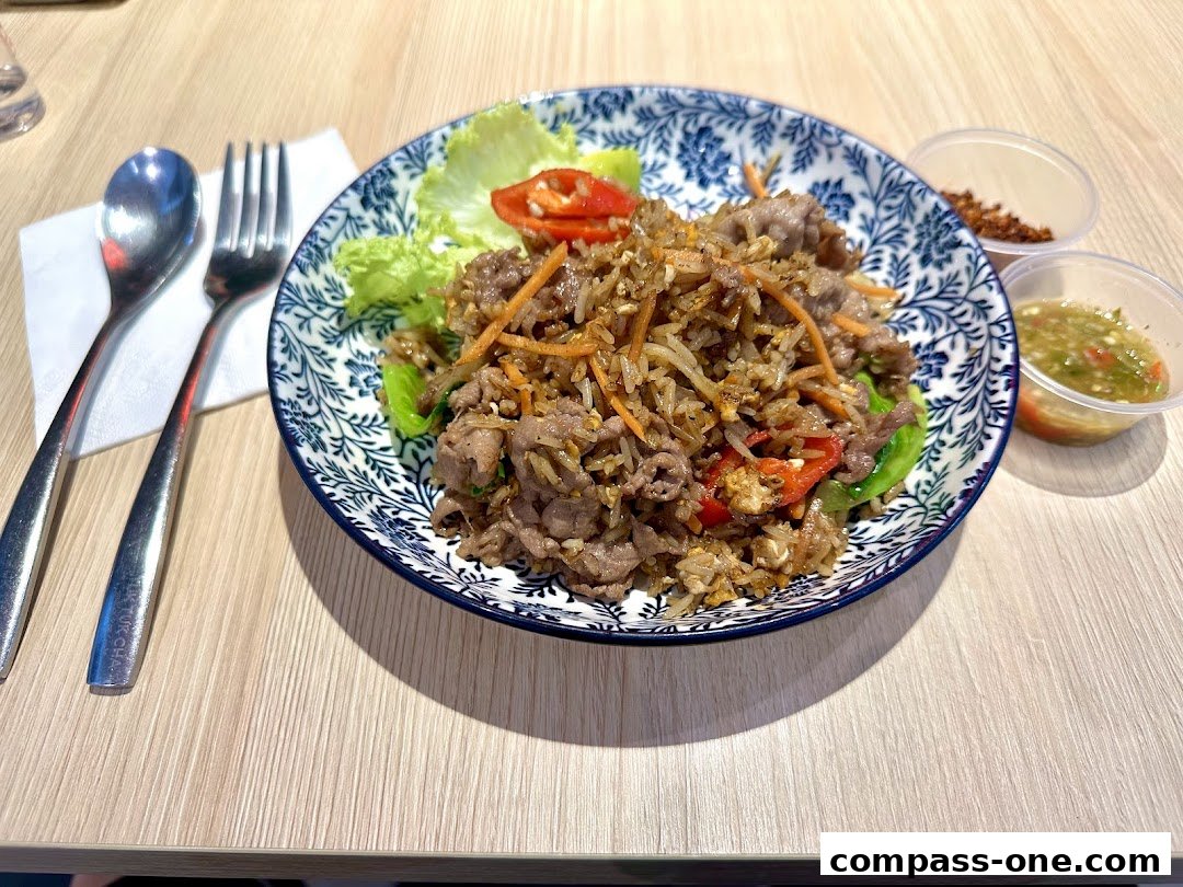 A plate of beef fried rice with chili and vegetables, served with dipping sauce.