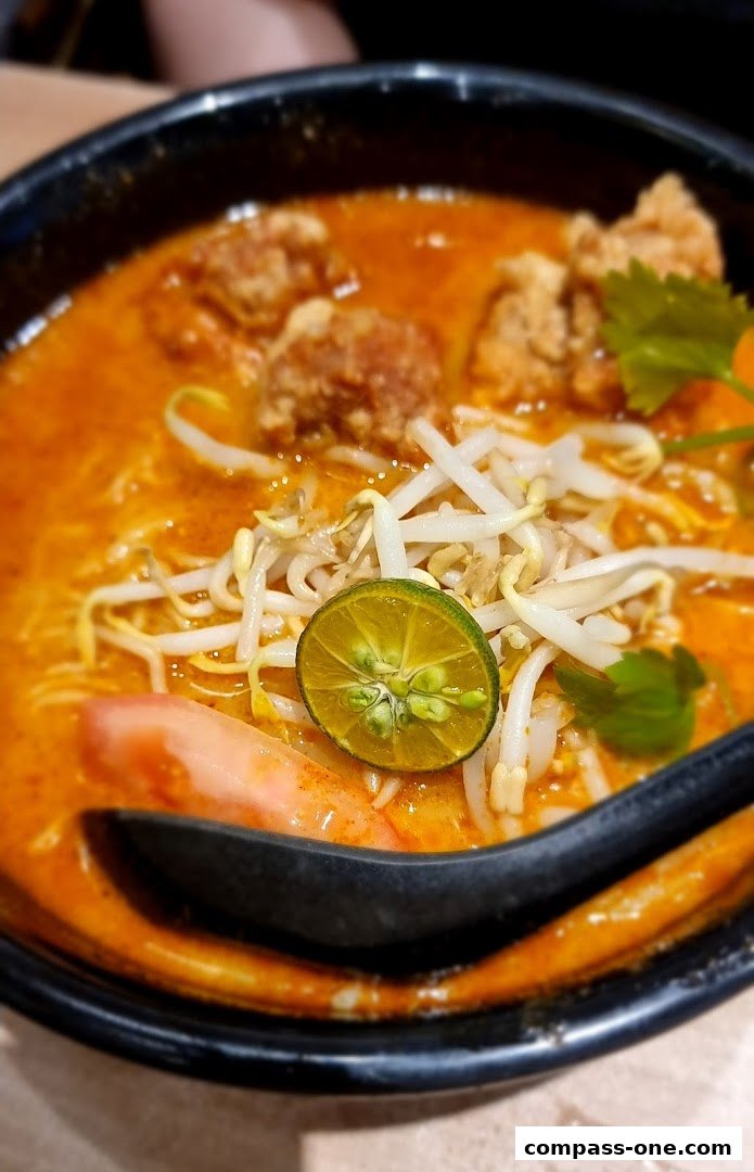 A close-up shot of a steaming bowl of Ajisen Ramen, featuring noodles, broth, and toppings.