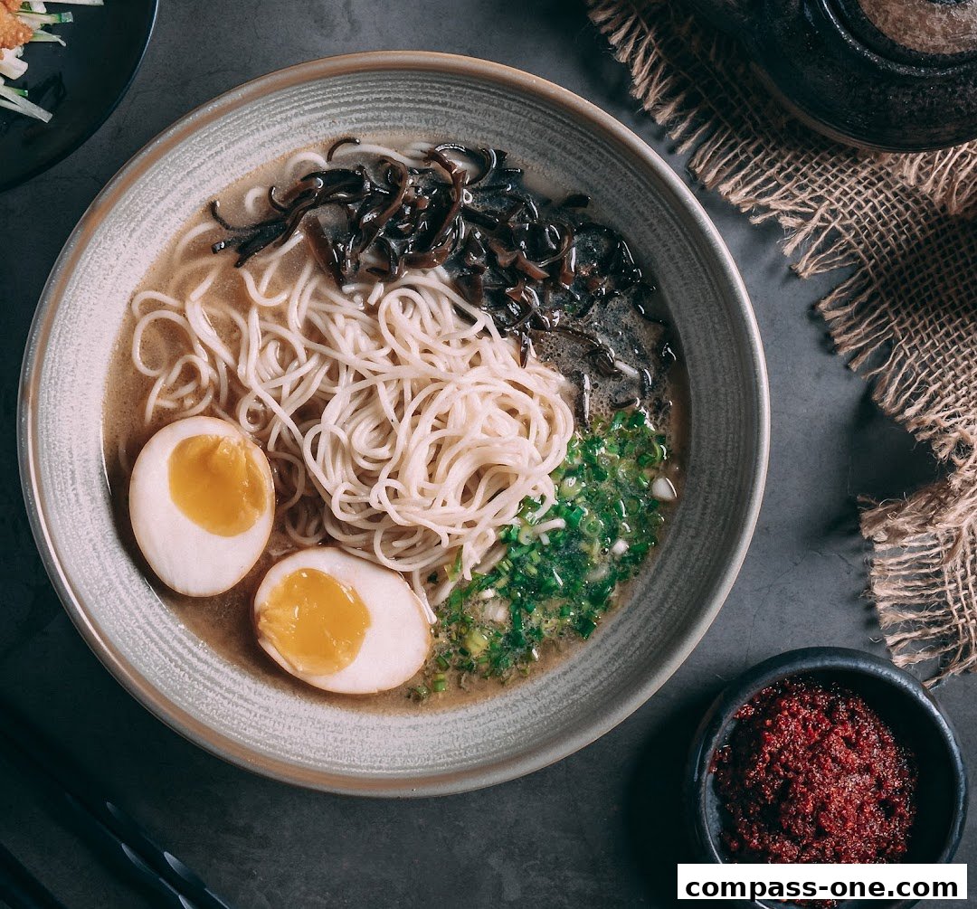 A delicious bowl of ramen with noodles, broth, eggs, and toppings, served with chili paste.