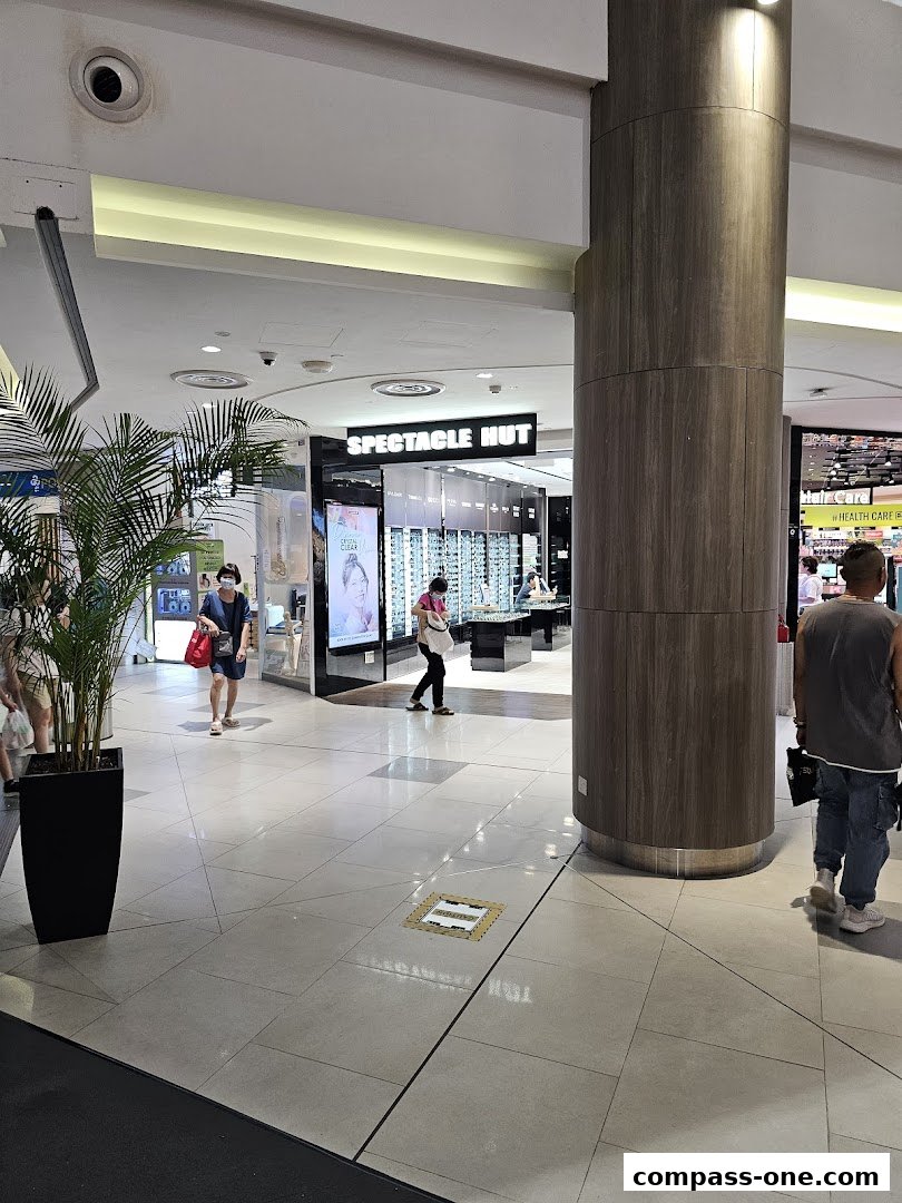 The entrance to Spectacle Hut, an optical shop, with displays of eyewear and customers browsing.